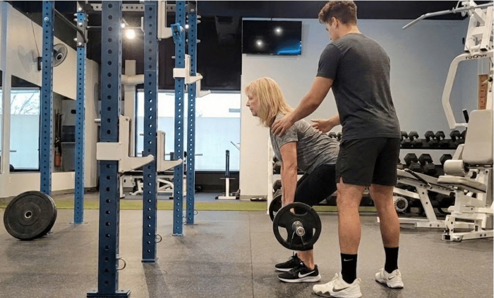 Personal trainer coaching client on deadlift technique for bone density improvement